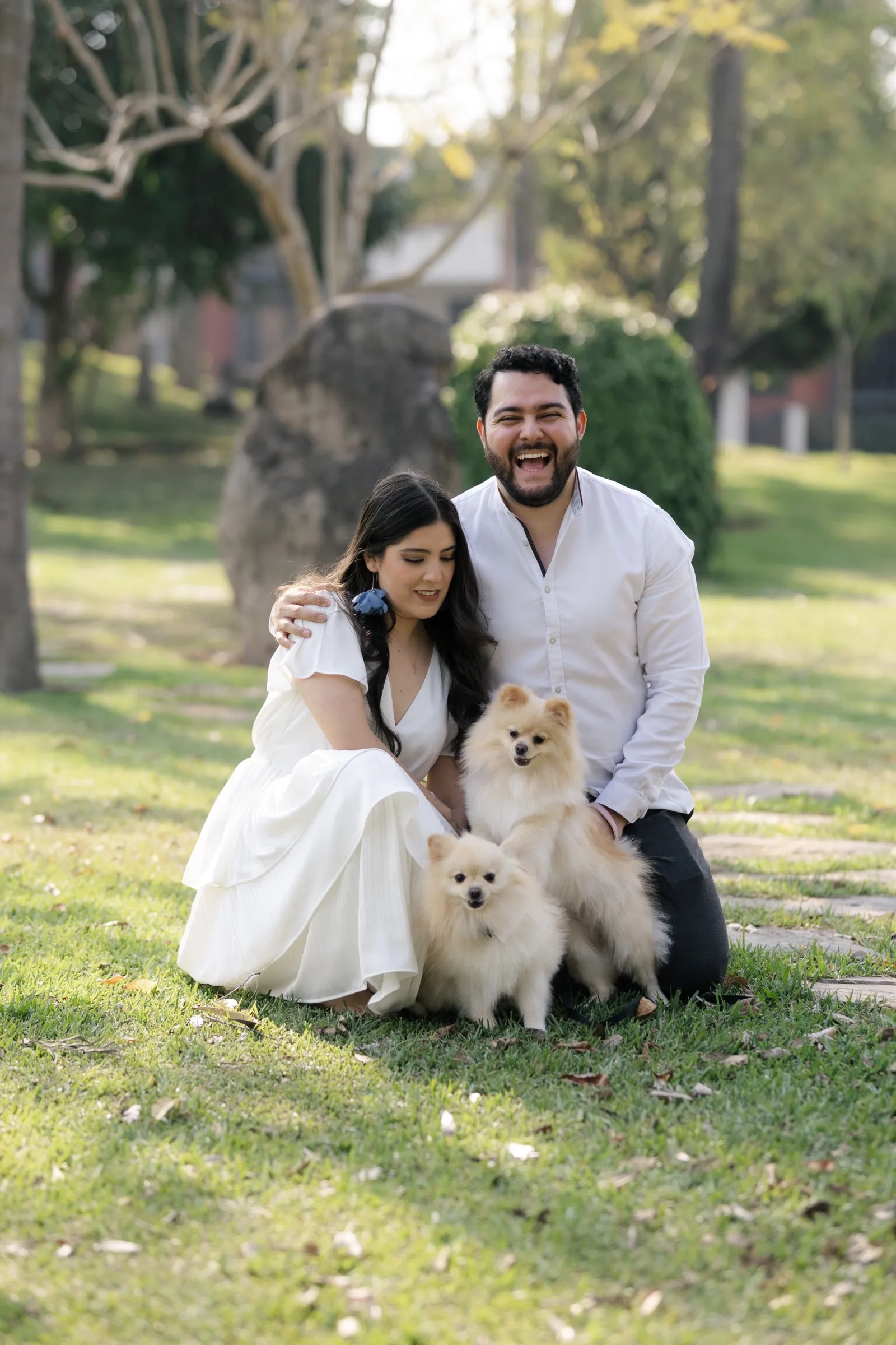 Josué y Katherine sentados en el césped con su perro blanco