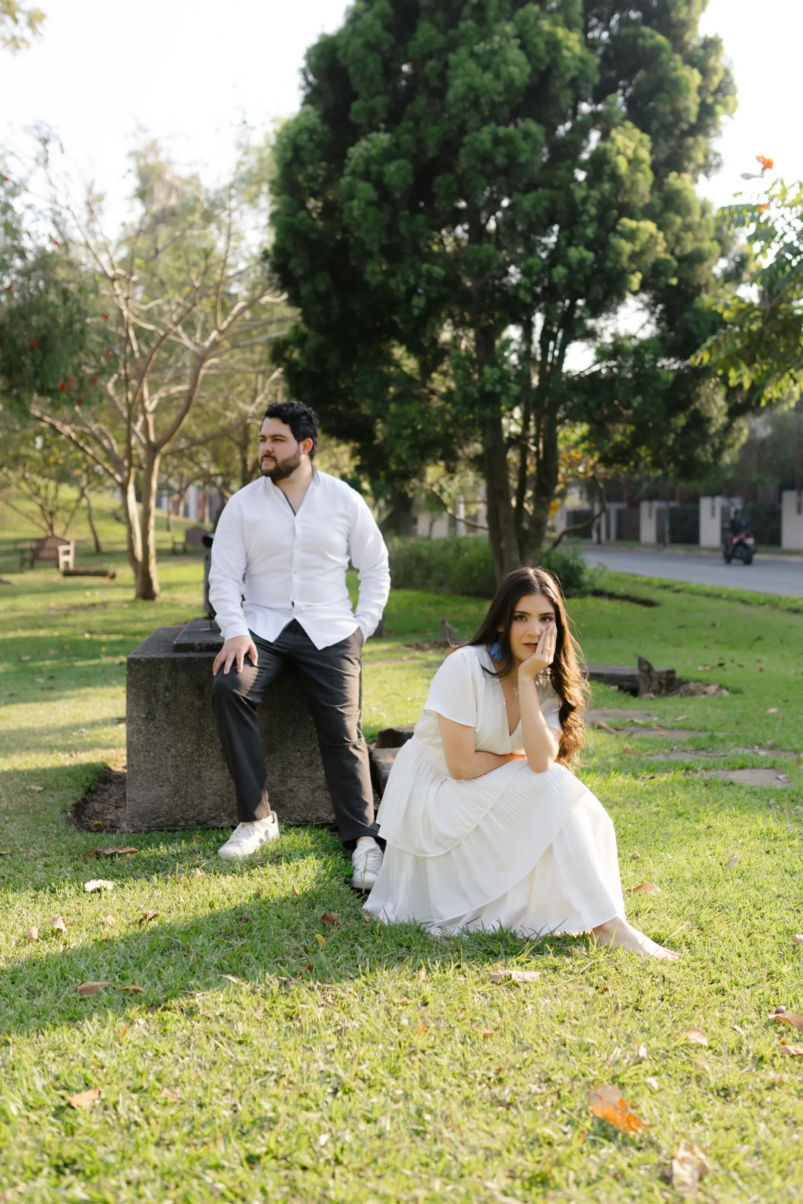 Josué sentado sobre una roca y Katherine a su lado sobre el césped, en un jardín